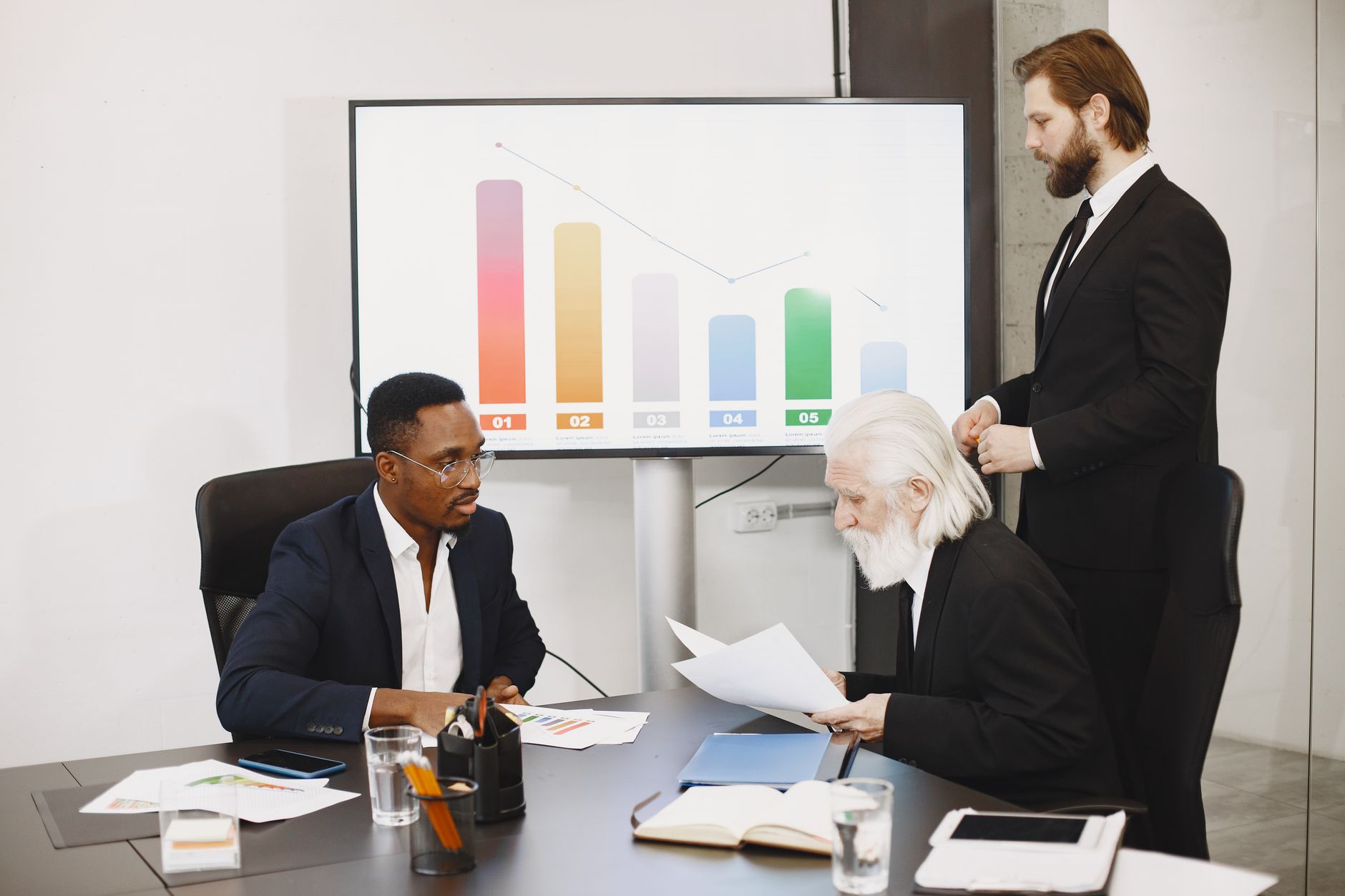 Two media executives analyzing a storyboard with data charts